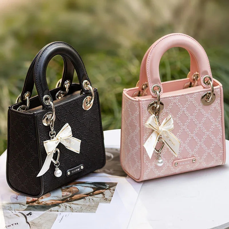 Black and pink Clarisse Bow Jacquard Handbags displayed outdoors, highlighting their elegant bow accents and structured mini tote design.