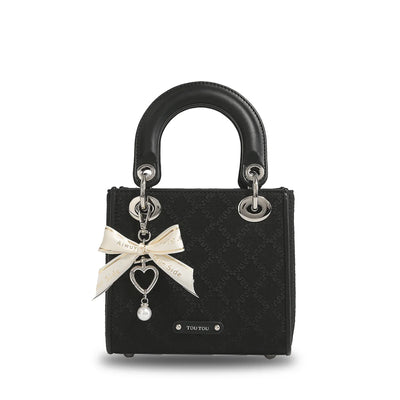 Clarisse Bow Jacquard Handbag in black with cream bow and heart charm, showcasing a classic jacquard pattern and silver-tone hardware.